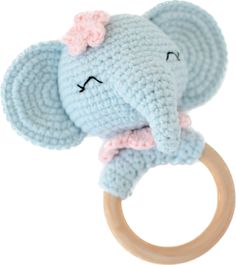 a crocheted elephant with a pink bow on it's head sitting on a wooden ring