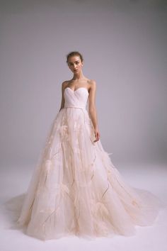 a woman in a wedding dress standing on a white background with her hands behind her back