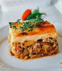 a piece of lasagna on a white plate with carrots and parsley