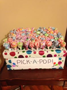 a box filled with lots of candy sitting on top of a wooden table next to a wall