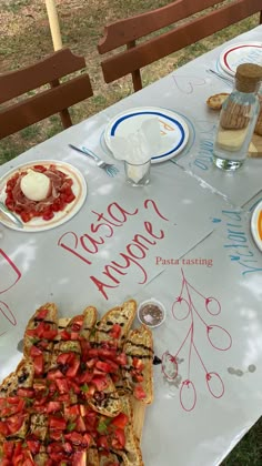 a table topped with lots of food on top of a white tablecloth covered in writing