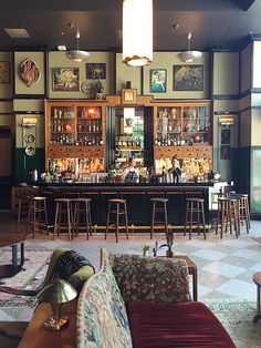 a bar with lots of stools and chairs around it in a room that has many pictures on the walls