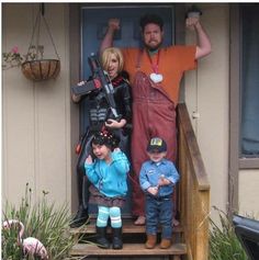 a man, woman and two children standing on the front steps of a house with their arms in the air