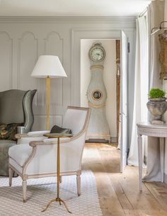 a living room filled with furniture and a clock mounted to the side of a wall