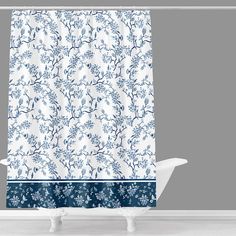 a shower curtain with blue and white floral designs on the bottom, in front of a gray wall