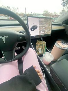 a woman sitting in the driver's seat of a car next to a cup of coffee