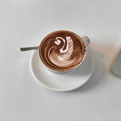 a cappuccino on a saucer next to a laptop