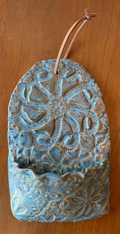 a blue vase sitting on top of a wooden table next to a brown leather cord