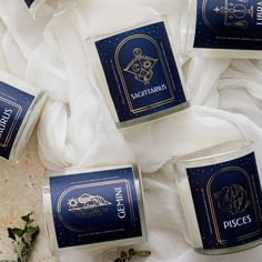 four candles are sitting next to each other on a white cloth with gold foil lettering