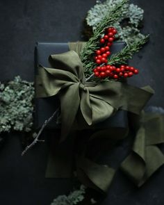 a present wrapped in green paper with red berries and greenery tied to the top