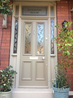 the front door to stockton house with potted plants on either side and glass paneled windows