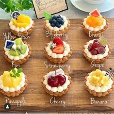 a wooden board topped with cupcakes covered in fruit