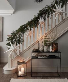 a christmas garland on the banister next to a table with candles and other decorations