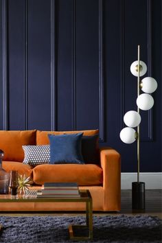 a living room with an orange couch, blue walls and a gold coffee table in front of it