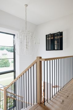 a chandelier hanging from the side of a wooden stair case next to a window