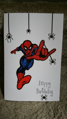 a spiderman birthday card with the words happy birthday on it, hanging from strings