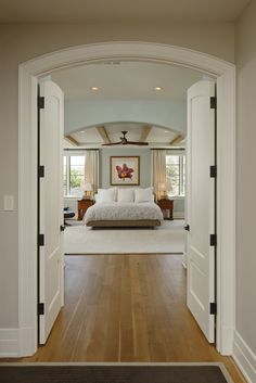 an open door leading to a bedroom with a large bed in the center and two lamps on either side