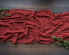 an overhead view of a red cloth on a wooden surface with greenery in the corner