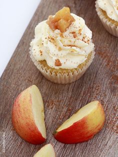 cupcakes with white frosting and apples on a cutting board