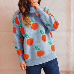 a woman wearing a blue sweater with oranges on it and holding her hand up to her mouth