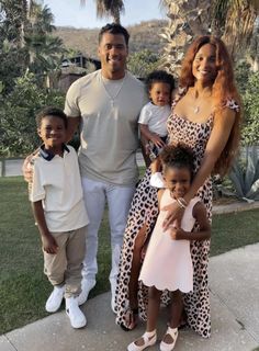 the couple and their children are posing for a photo in front of some palm trees