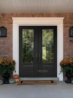 two black double doors with pumpkins and gourds on the front porch area