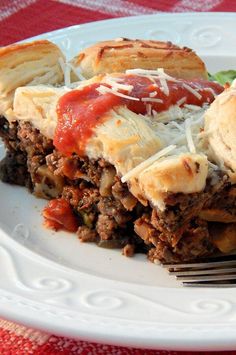 a piece of meat and cheese pie on a white plate with a red table cloth