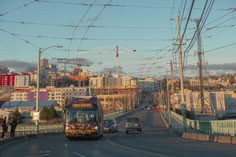 a bus driving down a street next to tall buildings and power lines in the background