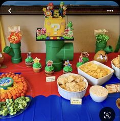 a table topped with lots of food and cupcakes on top of it's sides