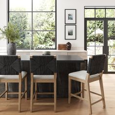 a dining room table with four chairs and a vase on the counter next to it