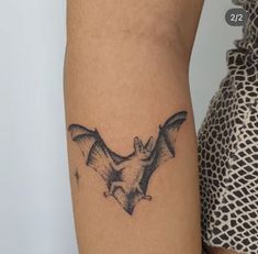 a small bat tattoo on the arm