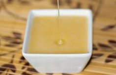 a small white bowl filled with liquid on top of a wooden table