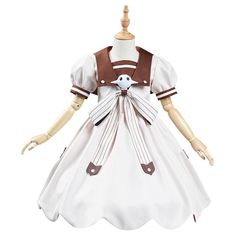 a doll wearing a white dress with brown trims and a bird on the chest