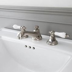 two chrome faucets sitting on top of a white sink