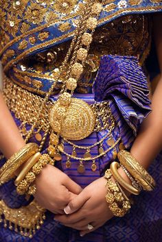 a woman in a blue and gold outfit with jewelry on her chest, wearing an elaborate necklace