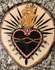 a wooden plaque with a heart and crown painted on it's side, sitting on a granite surface