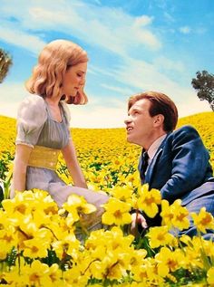 a man and woman sitting in a field of yellow flowers