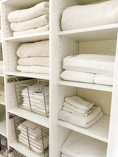 white linens are stacked on shelves in a closet