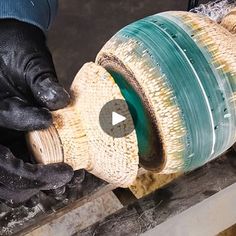 a person in black gloves is using a grinder on a piece of wood with green and white stripes