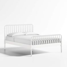 a white bed with two pillows on top of the headboard and foot board, in front of a white wall