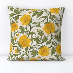 a yellow and green floral pillow sitting on top of a white table