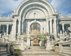 a large white building with statues on the front and stairs leading up to it's entrance