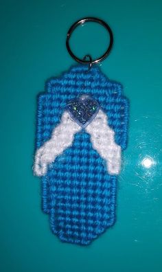 a crocheted keychain with a heart and angel wings on it sitting on a blue surface