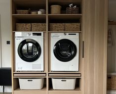 a washer and dryer sitting in front of a wooden shelf filled with baskets