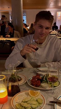 a man sitting at a table with plates of food and drinks in front of him