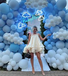 a woman standing in front of a blue and white balloon arch