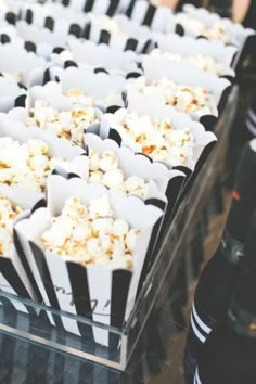 popcorn is sitting in black and white paper cups