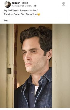 a man with curly hair wearing a blue shirt and jeans looking into the distance while standing in front of an open door