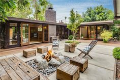 a patio with chairs and fire pit surrounded by trees