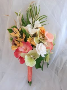 a bouquet of flowers is sitting on a white cloth covered surface, with greenery and foliage